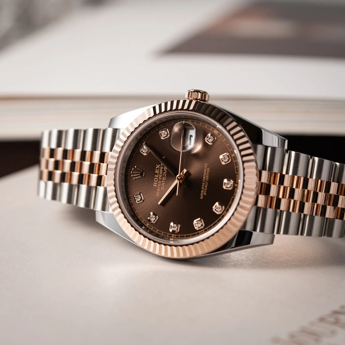 Rolex Datejust 41 126331 in Stahl-Roségold mit dem braunen Chocolate-Diamant-Zifferblatt liegt auf der Gehäuseflanke