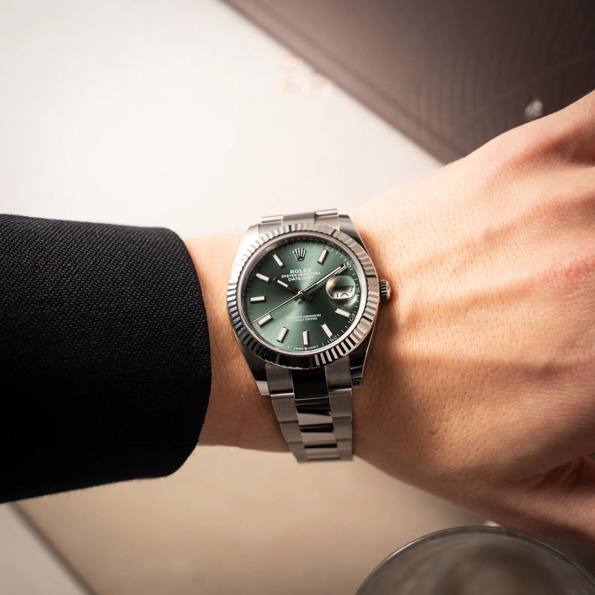 Mann trägt die Rolex Datejust 41 der Referenz 126334 mit dem grünem Zifferblatt am Oyster-Stahlband an seinem Handgelenk und präsentiert die Armbanduhr in die Kamera