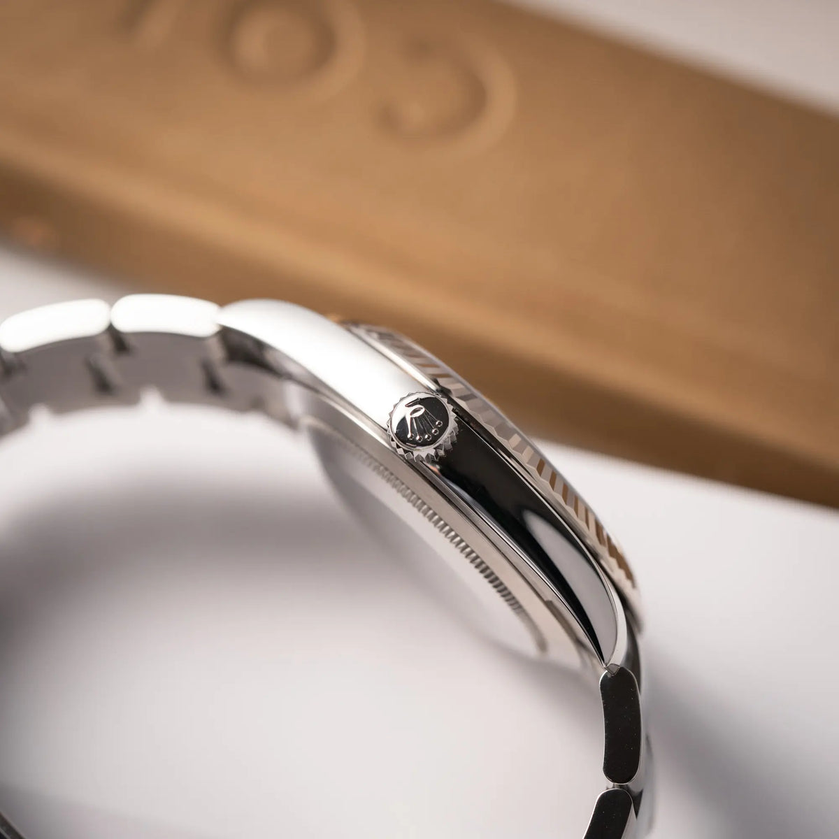 Produktfotografie zeigt die Aufzugskrone der Rolex Datejust 41 der Referenz 126334 mit geriffelter Weißgold-Lünette und Oyster-Stahlband mit dem grauen Wimbledon-Zifferblatt mit schwarz-grünen Indizes