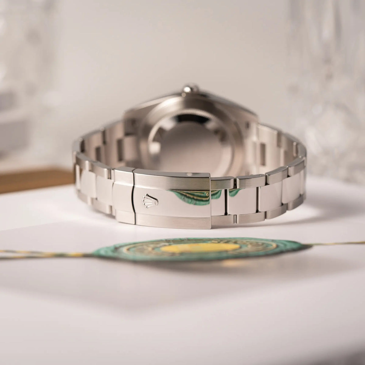 Produktfotografie zeigt das Oyster-Stahlband und die Oyster-Stahl-Faltschliesse der Rolex Datejust 41 der Referenz 126334 mit geriffelter Weißgold-Lünette mit dem grauen Wimbledon-Zifferblatt mit schwarz-grünen Indizes