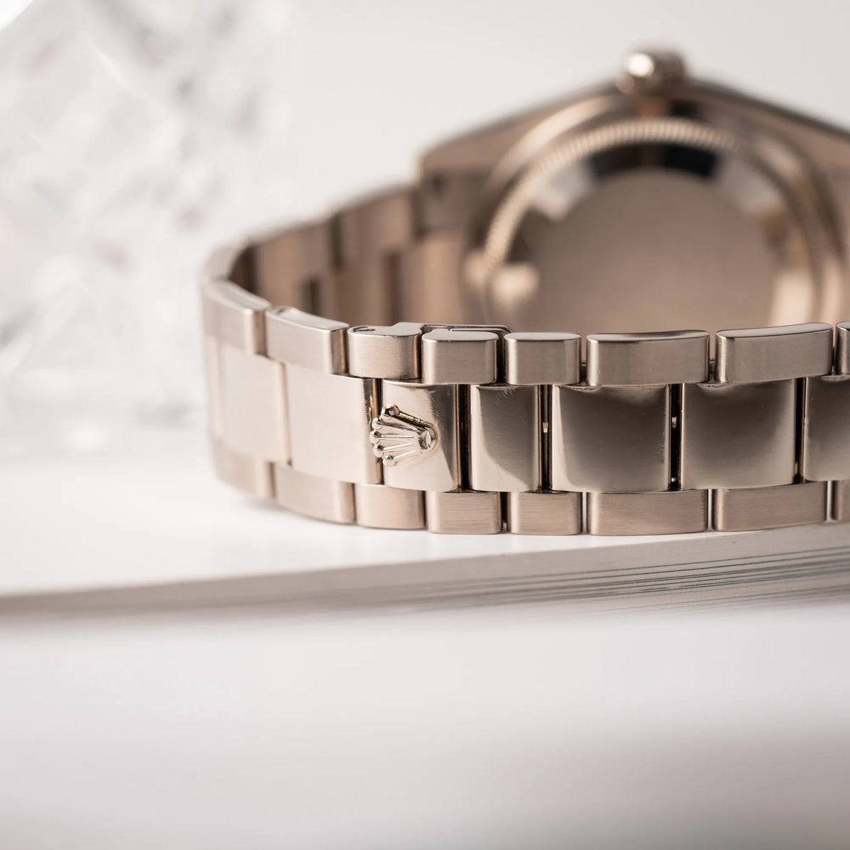 Detailaufnahme der Rolex-Krone an der verdeckten Faltschliesse der Rolex Day-Date 36 Armbanduhr in Weißgold der Referenz 118239 mit weißem Zifferblatt mit römischen Indizes am Oyster-Weißgold-Armband