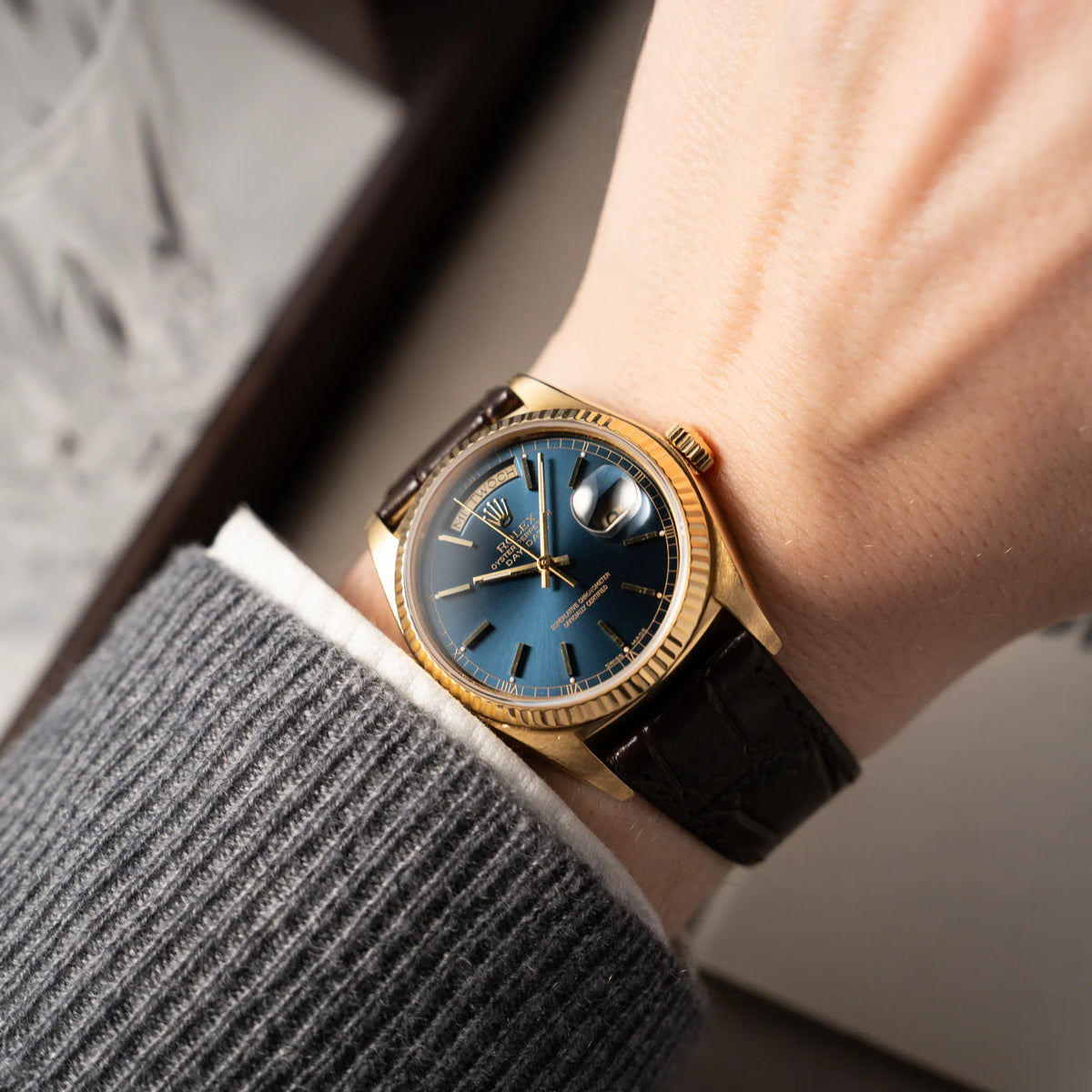 Wristshot mit der Rolex Day-Date 36 der Referenz 18038 in Gelbgold mit blauem Zifferblatt am braunen Lederband
