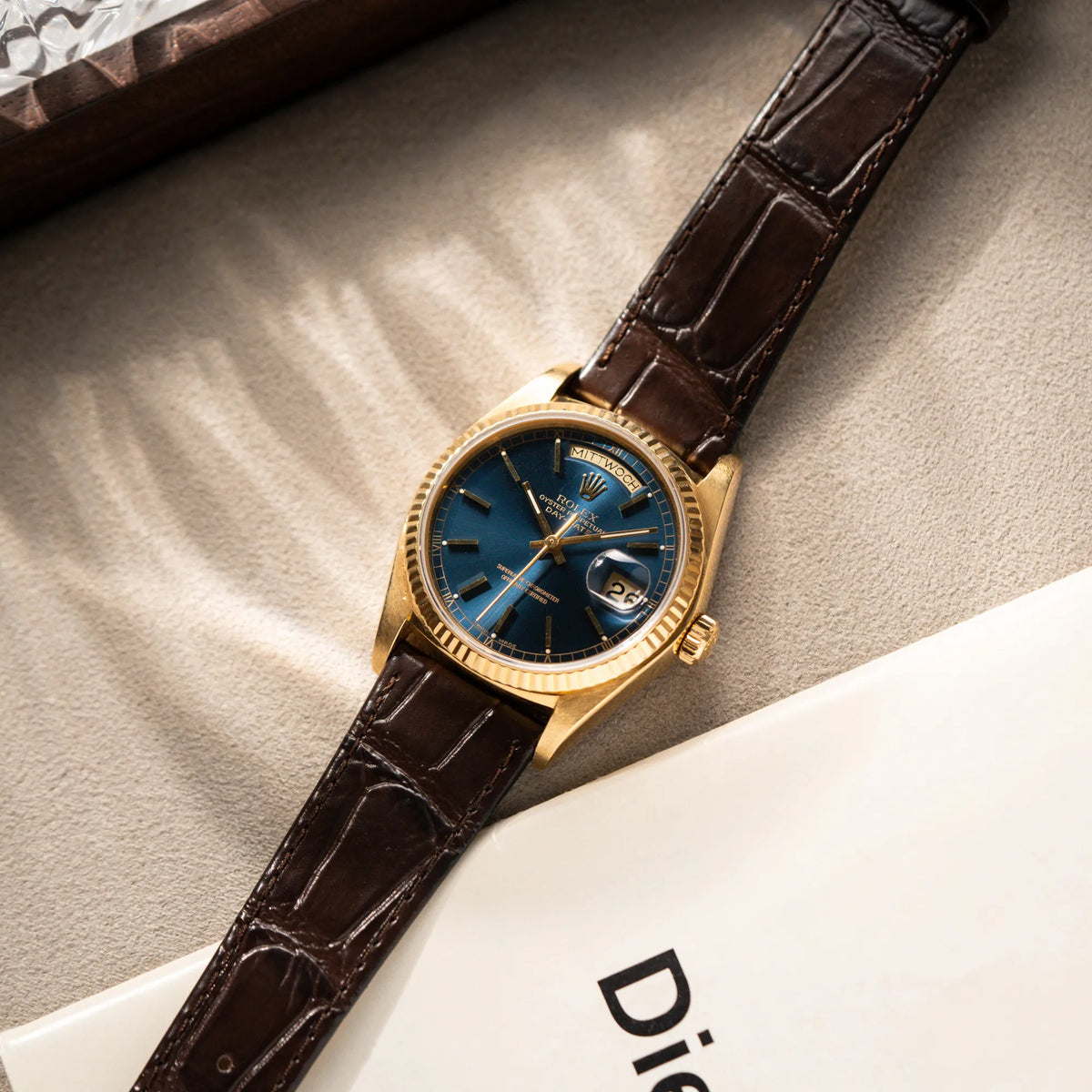 Produktfotografie der Rolex Day-Date 36 der Referenz 18038 in Gelbgold mit blauem Zifferblatt am braunen Lederband