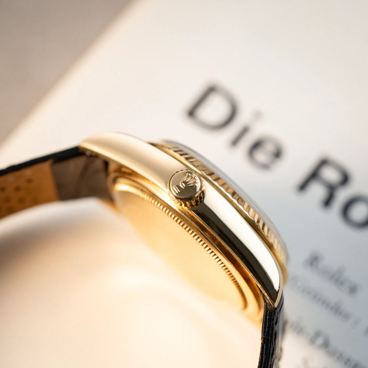 Produktfoto der Rolex Day-Date 36 der Referenz 18038 in Gelbgold mit blauem Zifferblatt am braunen Lederband mit Fokus auf dem seitlichen Gehäuse und Aufzugskrone