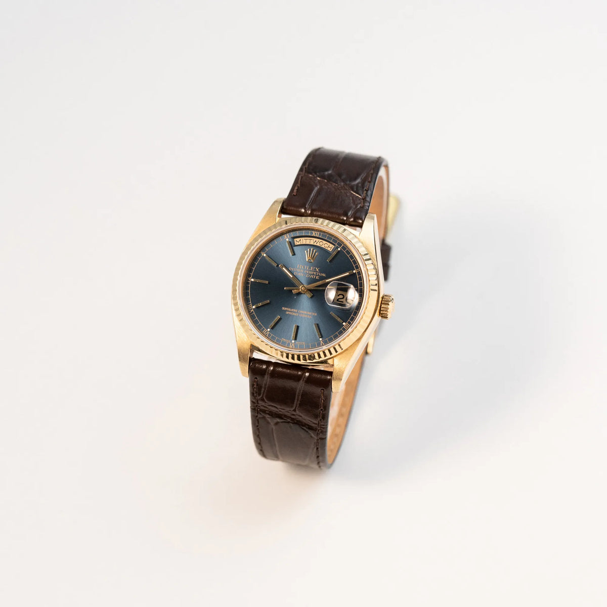 Leicht schräge Ansicht der Rolex Day-Date 36 der Referenz 18038 in Gelbgold mit blauem Zifferblatt am braunen Lederband