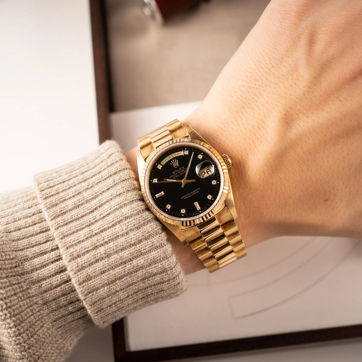 Mann trägt die Rolex Day-Date 36 in Gelbgold mit der Referenznummer 18238 mit englischer Tagesanzeige, mit schwarzem Lack-Zifferblatt und Diamant-Indizes für einen Wristshot am Handgelenk