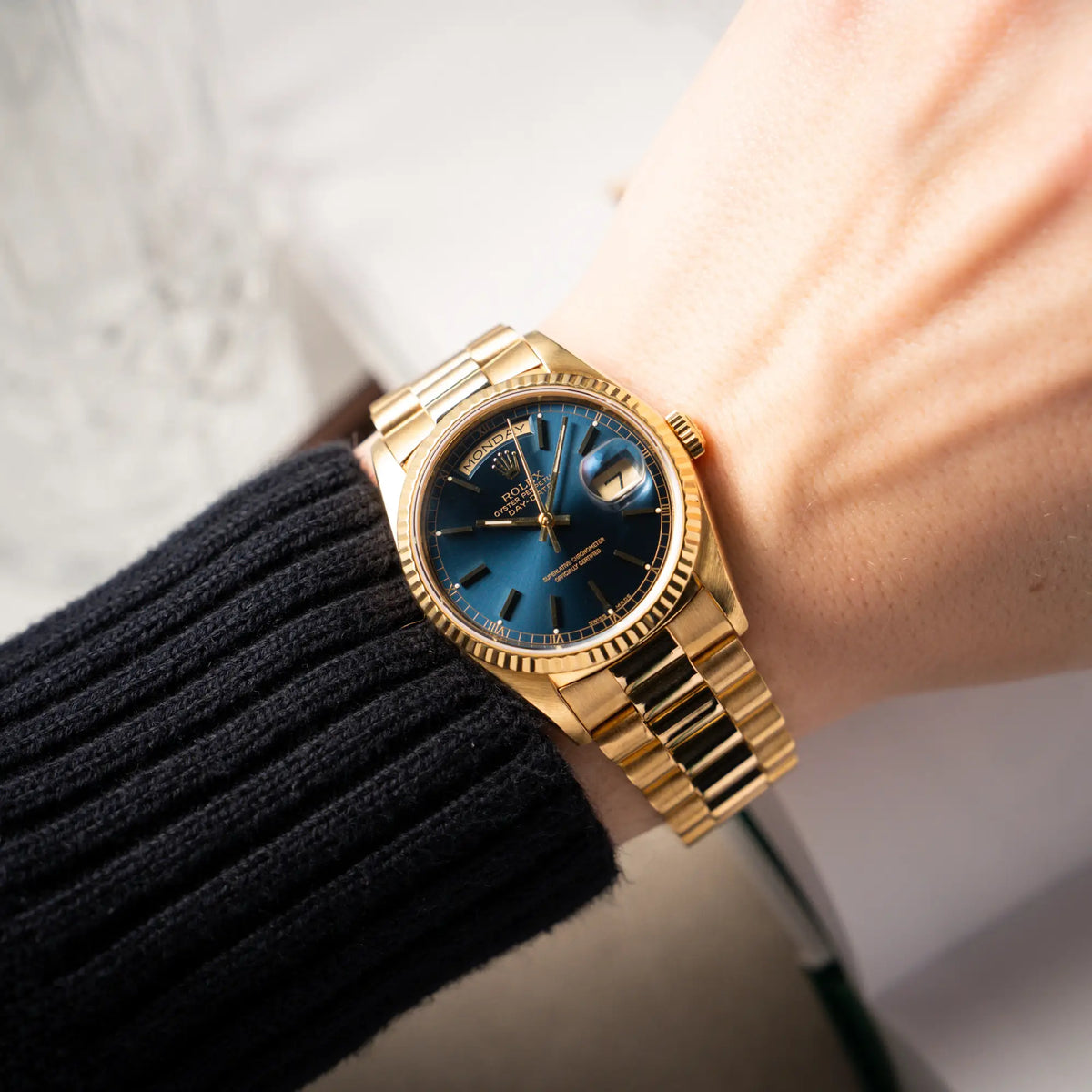 Mann trägt die gelbgoldenen Rolex Day-Date 36 der Referenz 18238 mit blauem Zifferblatt und englisch-sprachiger Tagesanzeige an seinem Handgelenk