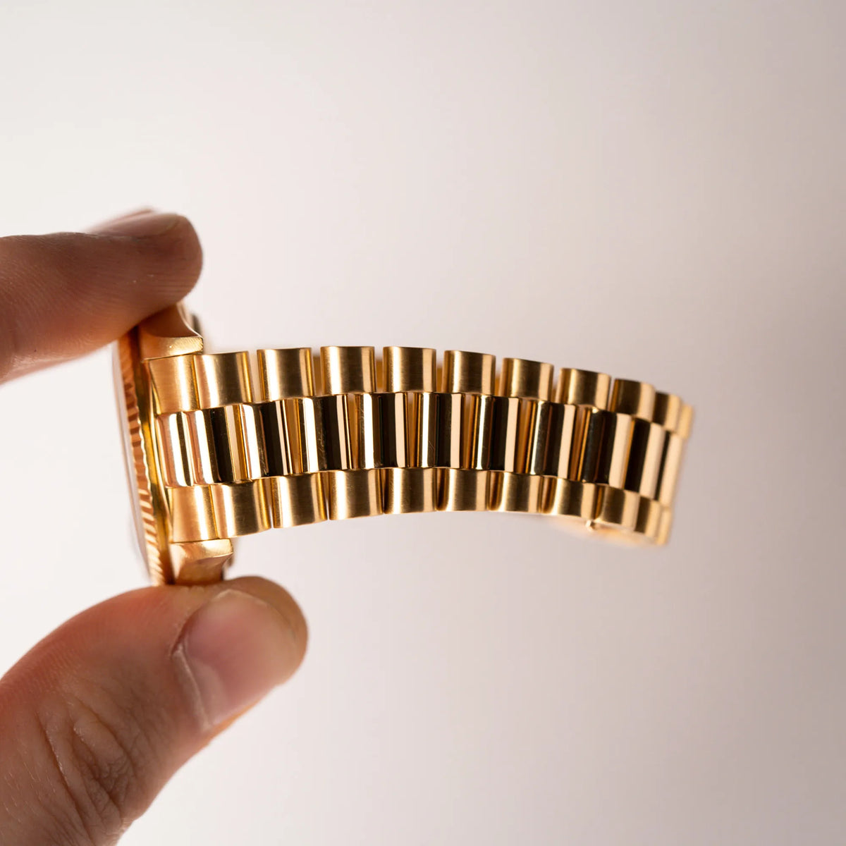 Mann hält die gelbgoldene Rolex Day-Date 36 der Referenz 18238 mit blauem Zifferblatt und englisch-sprachiger Tagesanzeigeund zeigt den Zustand /Stretch des President-Armbands auf