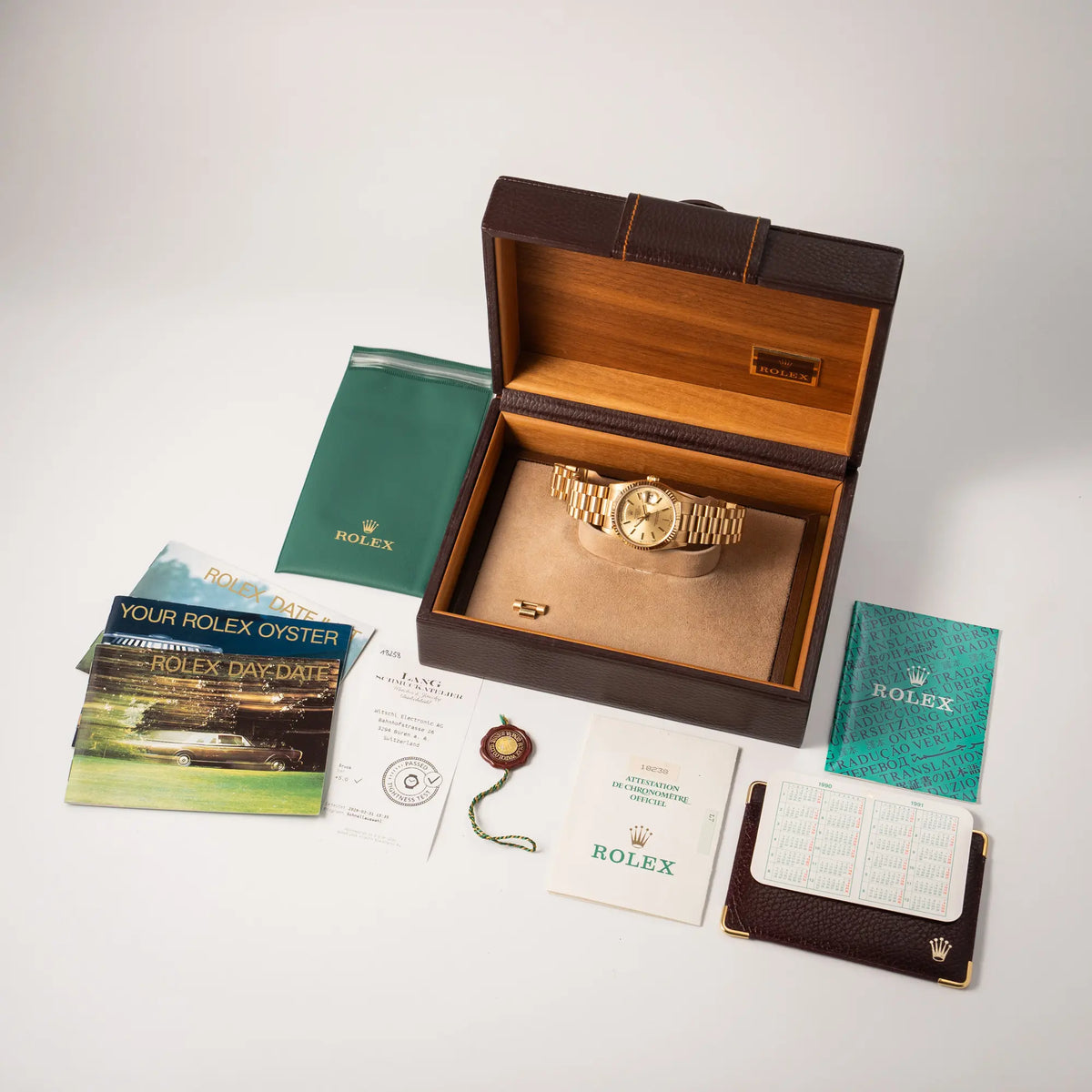Lieferumfang zu der Rolex Day-Date 36 der Referenz 18238 in Gelbgold mit champagnerfarbenem Stick-Dial, bestehend aus Box, Booklets, originaler Garantiekarte, Rolex-Etui mit Kalender und einem Wasserdichtheits-Test