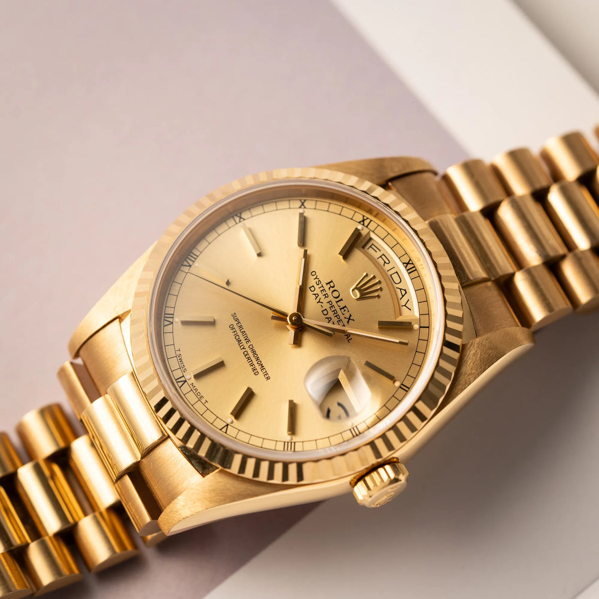 Nahe Produktfotografie der auf einem Buch liegenden Rolex Day-Date 36 der Referenz 18238 in Gelbgold mit champagnerfarbenem Stick-Dial