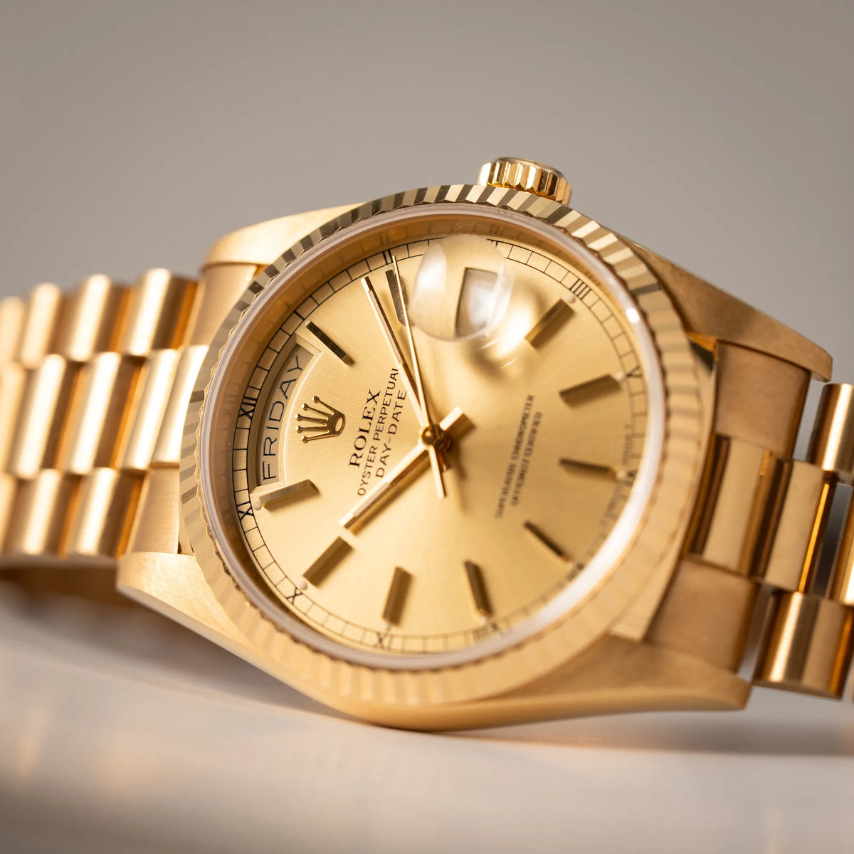 Produktfotografie der Rolex Day-Date 36 der Referenz 18238 in Gelbgold mit champagnerfarbenem Stick-Dial mit Fokus auf der Wochentagesanzeige bei 12 Uhr