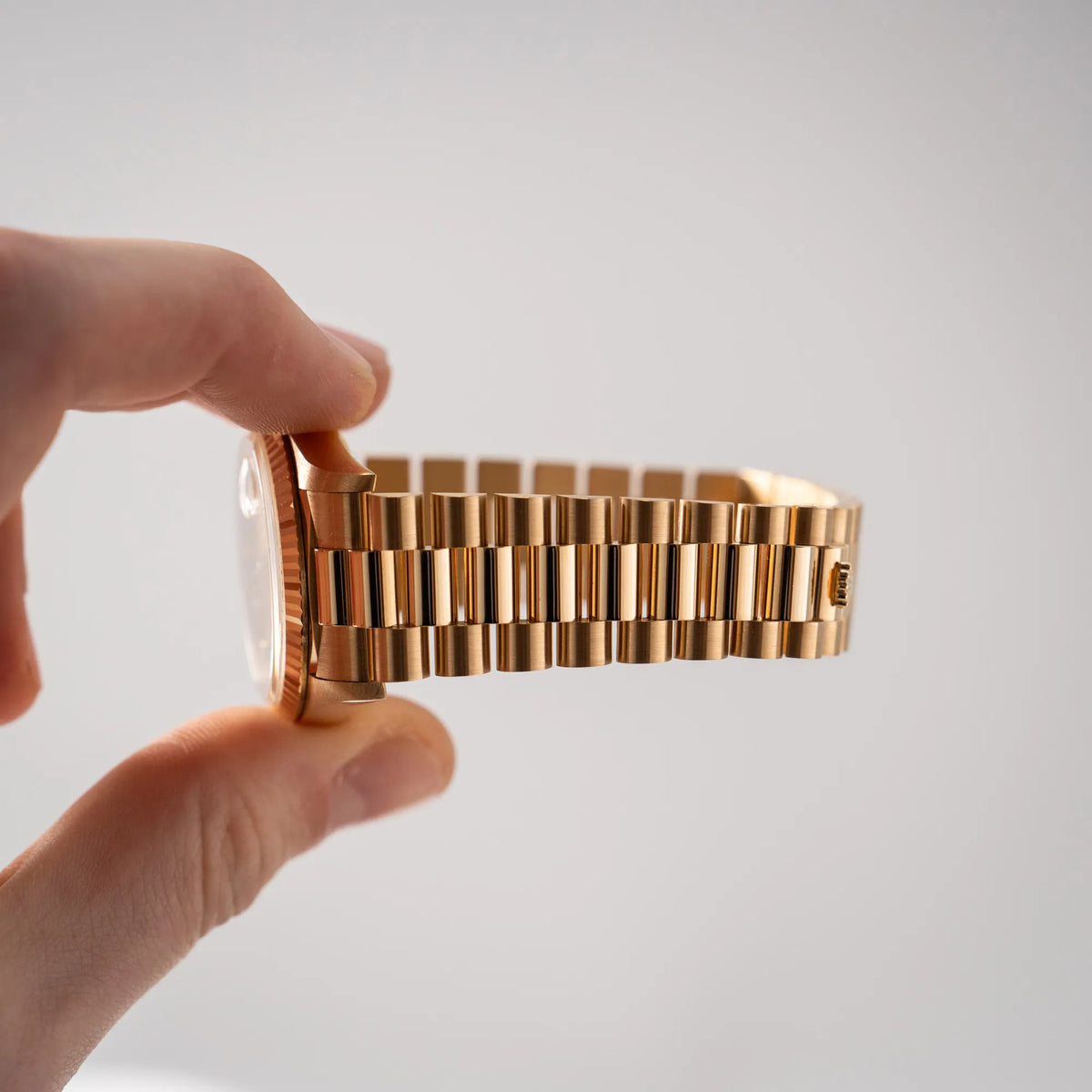 Mann hält die Rolex Day-Date 36 aus 1991 der Referenz 18238 mit goldfarbenem Zifferblatt und Diamant Indizes in einem hervorragenden Gesamtzustand zwischen den Fingern und zeigt den nicht vorhandenen Stretch des President-Armbands