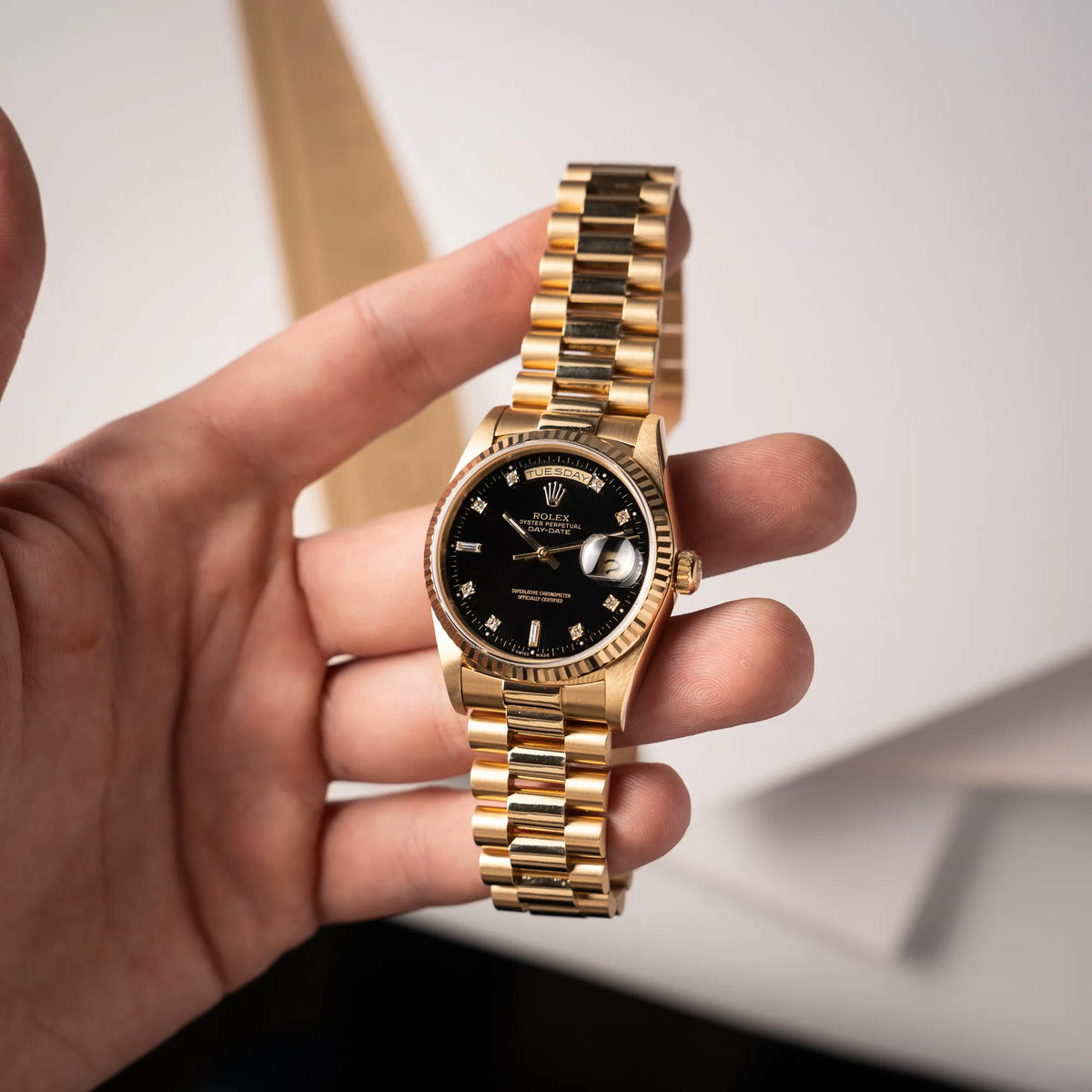 Mann hält die Rolex Day-Date 36 der Referenz 18238 in Gelbgold mit schwarzen Diamond-Dial am President-Armband in seiner Hand und präsentiert die Uhr in die Kamera