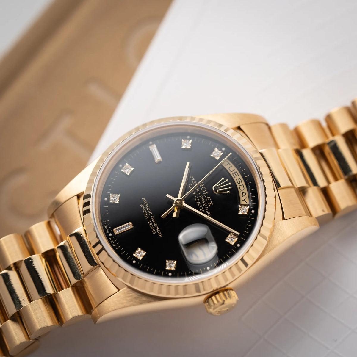 Detailaufnahme der Rolex Day-Date 36 der Referenz 18238 in Gelbgold mit schwarzen Diamond-Dial am President-Armband mit Fokus auf der Wochentagsanzeige