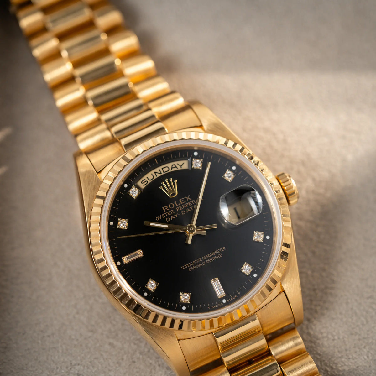 Produktfotografie der Rolex Day-Date 36 der Referenz 18238 im klassischen Gelbgold mit einem schwarzen Diamond Dial und englischsprachiger Wochentagsanzeige
