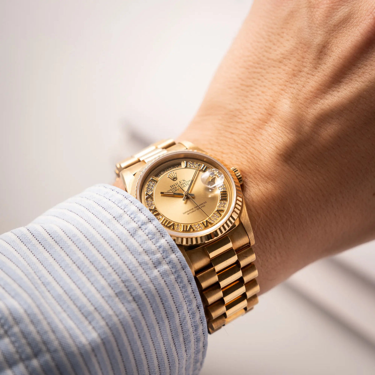 Wristshot mit der gelbgoldenen Rolex Day-Date 36 der Referenz 18238 mit einem seltenen Myriad-Dial mit Diamant-Kranz und römischen Indizes an einem Männerhandgelenk