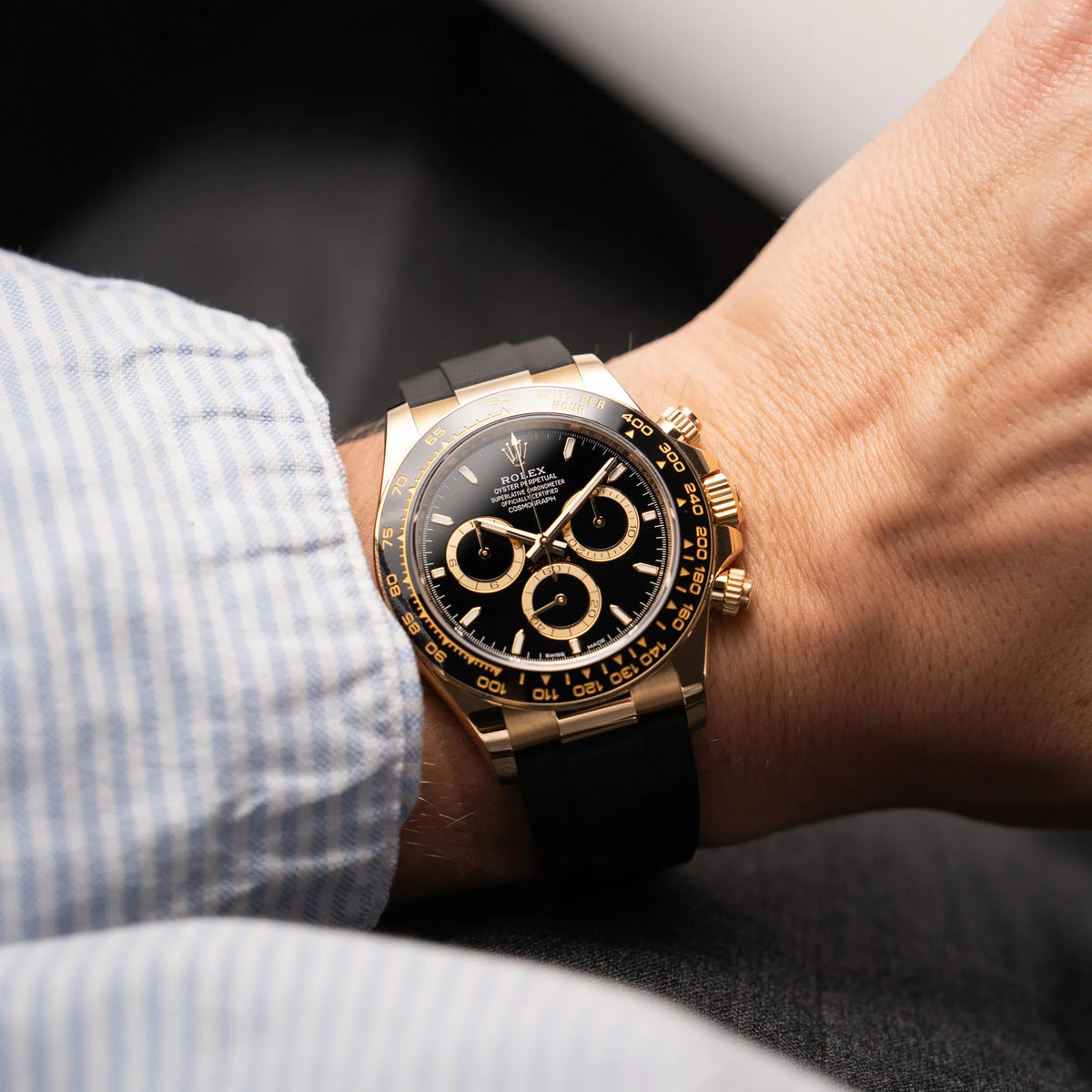 Mann trägt die Rolex Daytona 126518LN mit Gelbgold-Gehäuse und schwarzem Zifferblatt am schwarzen Oysterflex-Armband aus Kautschuk für einen Wristshot an seinem Handgelenk