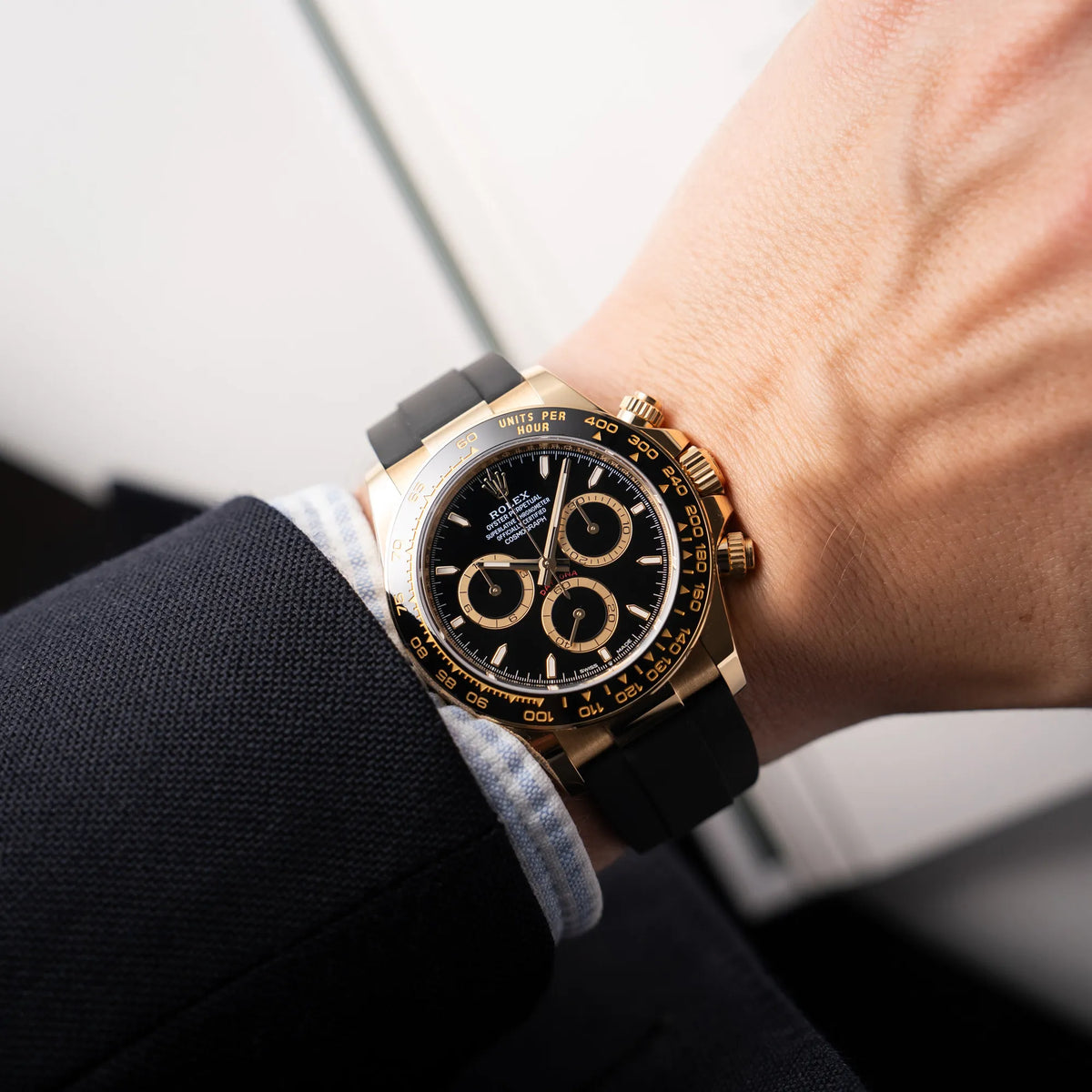 Mann trägt die Rolex Daytona 126518LN mit Gelbgold-Gehäuse und schwarzem Zifferblatt am schwarzen Oysterflex-Armband aus Kautschuk an seinem Handgelenk