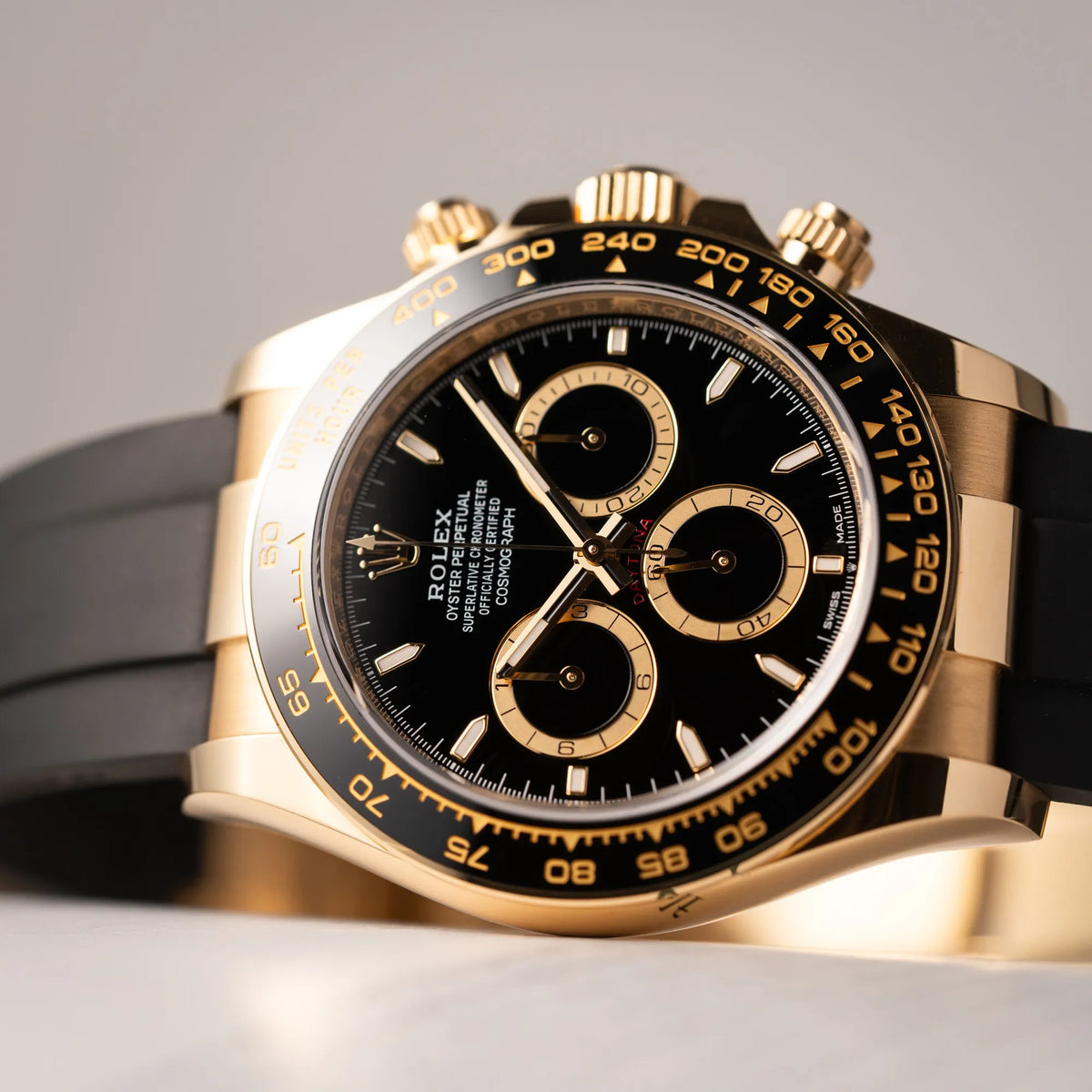 Detailaufnahme der Rolex Daytona 126518LN mit Gelbgold-Gehäuse und schwarzem Zifferblatt mit rotem Daytona-SChriftzugam schwarzen Oysterflex-Armband aus Kautschuk