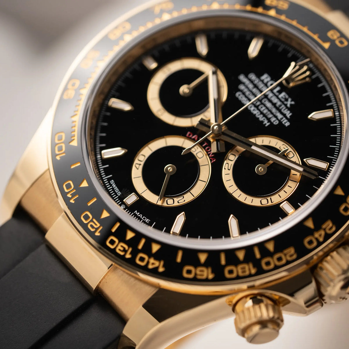 Detailaufnahme der Rolex Daytona 126518LN mit Gelbgold-Gehäuse und schwarzem Zifferblatt am schwarzen Oysterflex-Armband aus Kautschuk mit Fokus auf der Keramik-Lünette mit mit Tachymetre-Anzeige