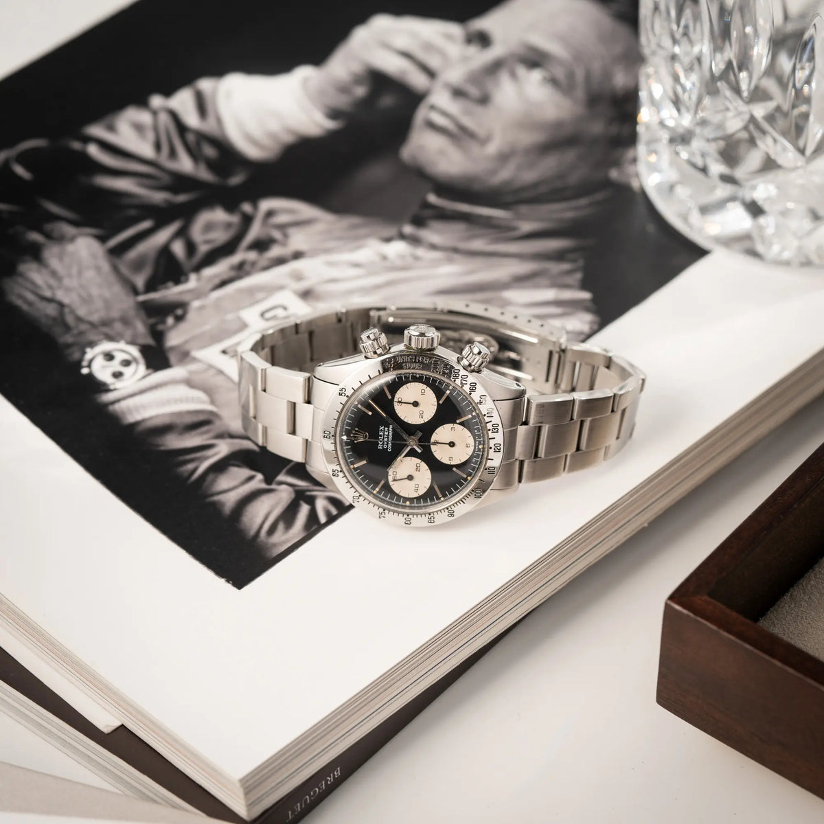 Rolex Daytona der Referenz 6265 mit Sigma-Dial in schwarz und weißen Sub-Dials im 37mm-Gehäuse aus den 70er Jahren liegt auf einem Buch wo Paul Newman zu sehen ist