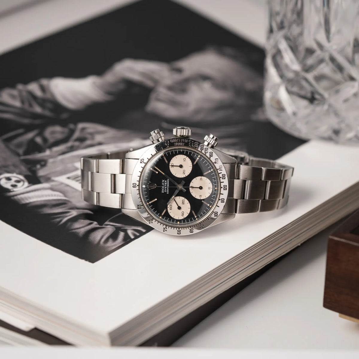 Produktfotografie der seitlich auf dem Uhrengehäuse liegenden Rolex Daytona der Referenz 6265 mit Sigma-Dial in schwarz und weißen Sub-Dials im 37mm-Gehäuse aus den 70er Jahren