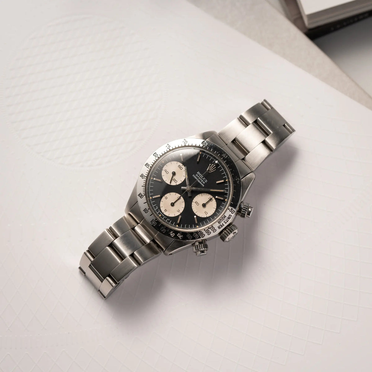 Produktfoto der flach auf einem Buch liegenden Rolex Daytona der Referenz 6265 mit Sigma-Dial in schwarz und weißen Sub-Dials im 37mm-Gehäuse aus den 70er Jahren