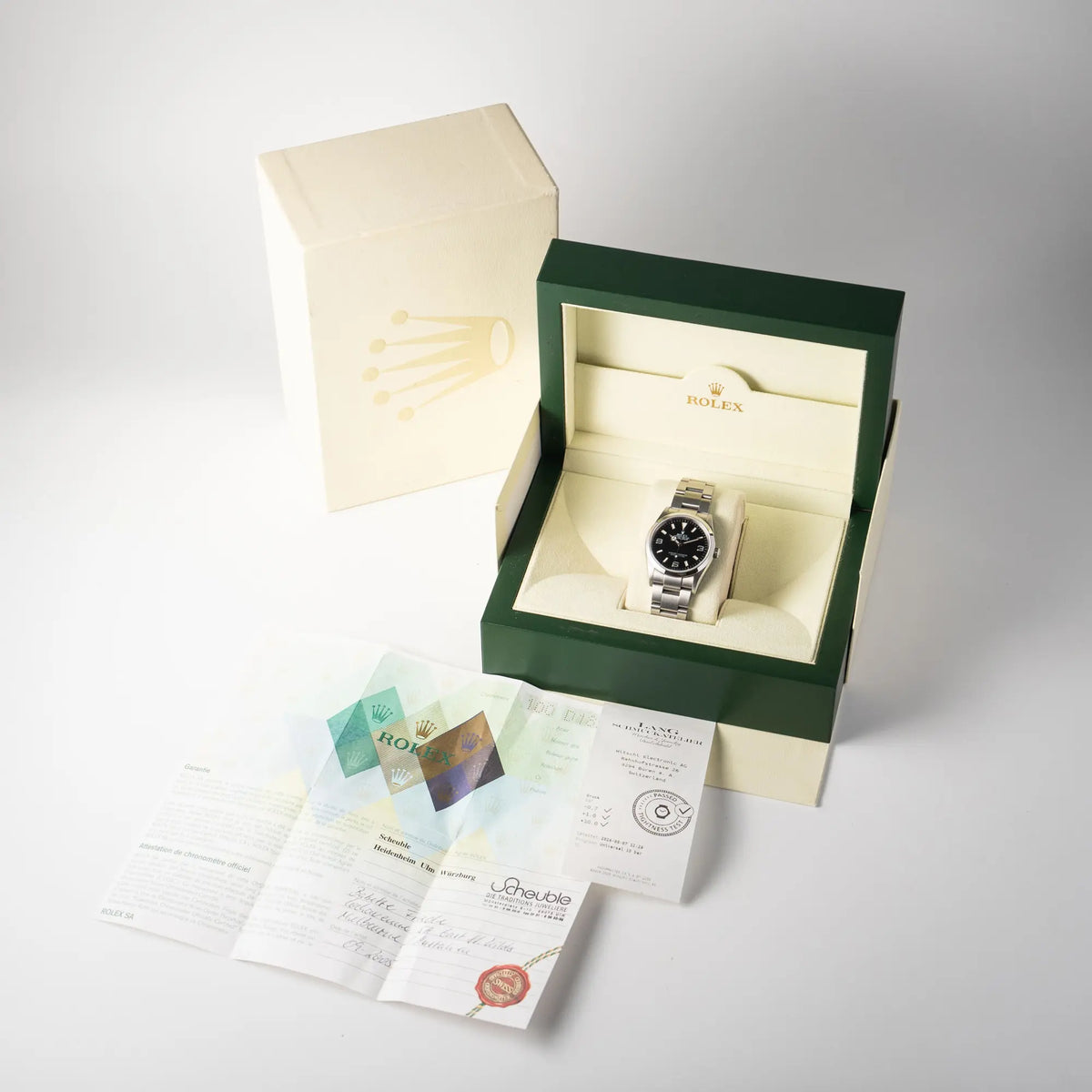 Lieferumfang zu der Rolex Explorer 36 der Referenz 114270 mit dem klassischen schwarzen 3-6-9-Explorer-Zifferblatt am Oyster-Stahlband,  bestehend aus Box mit Umkarton, original Papieren und Wasserdichtheitstes