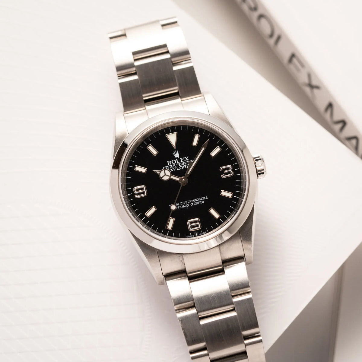 Rolex Explorer 36 der Referenz 114270 mit dem klassischen schwarzen 3-6-9-Explorer-Zifferblatt am Oytser-Stahlband liegt auf einem Uhrenbuch