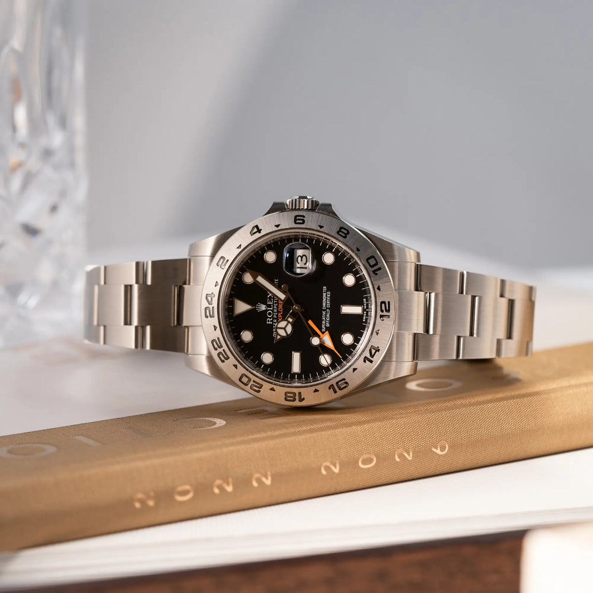 Produktfotografie der seitlich auf der Gehäuseflanke liegenden Rolex Explorer 2 Orangehand im Top-Zustand der Referenz 216570 mit schwarzem Zifferblatt 