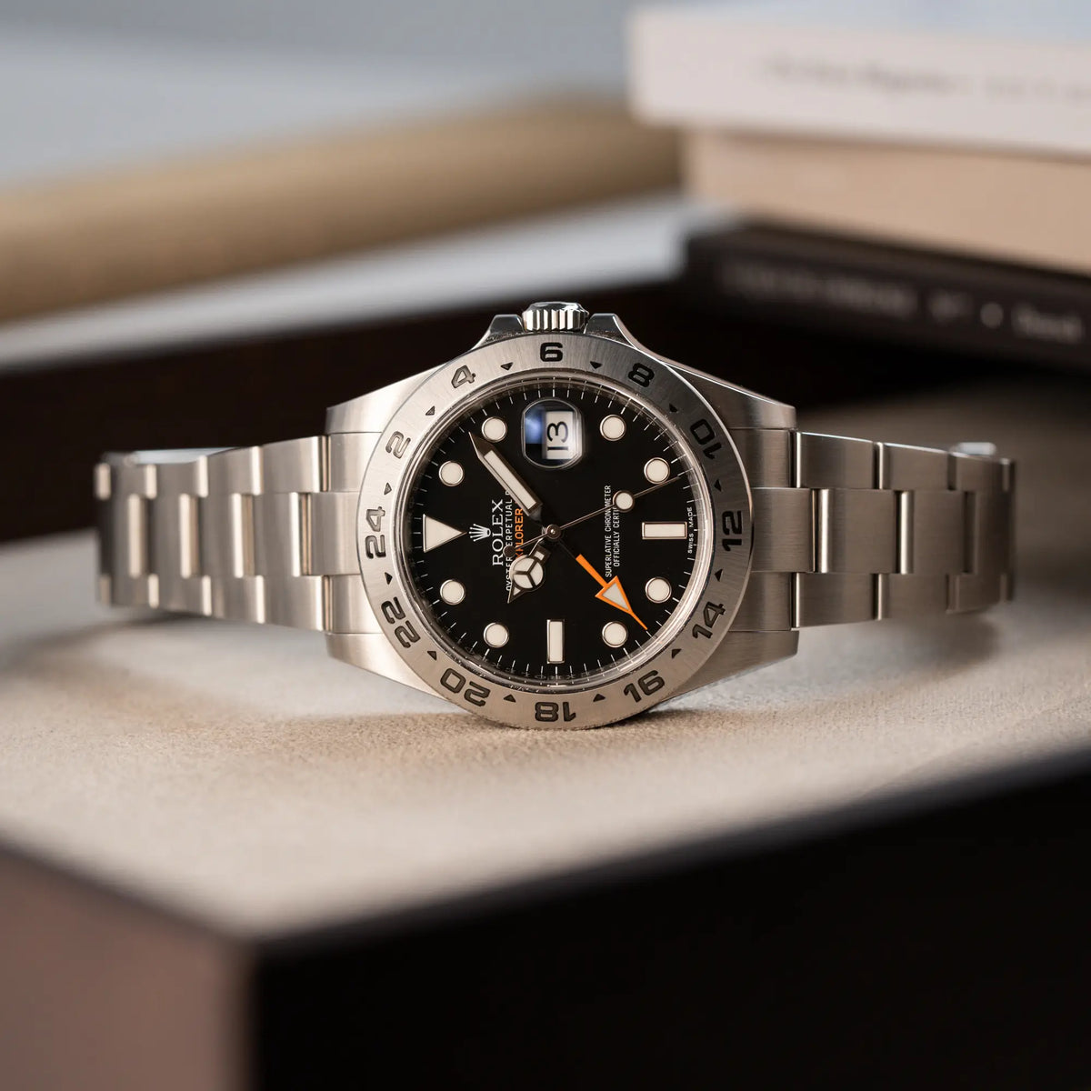 Produktfotografie der seitlich auf dem Gehäuse liegenden Rolex Explorer 2 Orangehand im Top-Zustand der Referenz 216570 mit schwarzem Zifferblatt 
