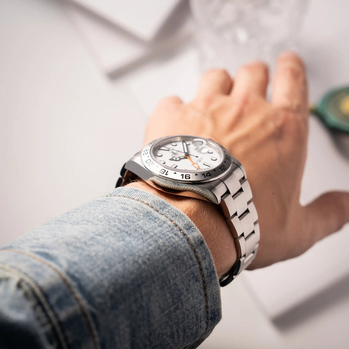 Mann präsentiert die Rolex Explorer II der Referenz 226570 am Oyster-Stahlband mit dem weißen Polar-Zifferblatt und dem typischen orangen 24-Stunden-Zeiger an seinem Handgelenk