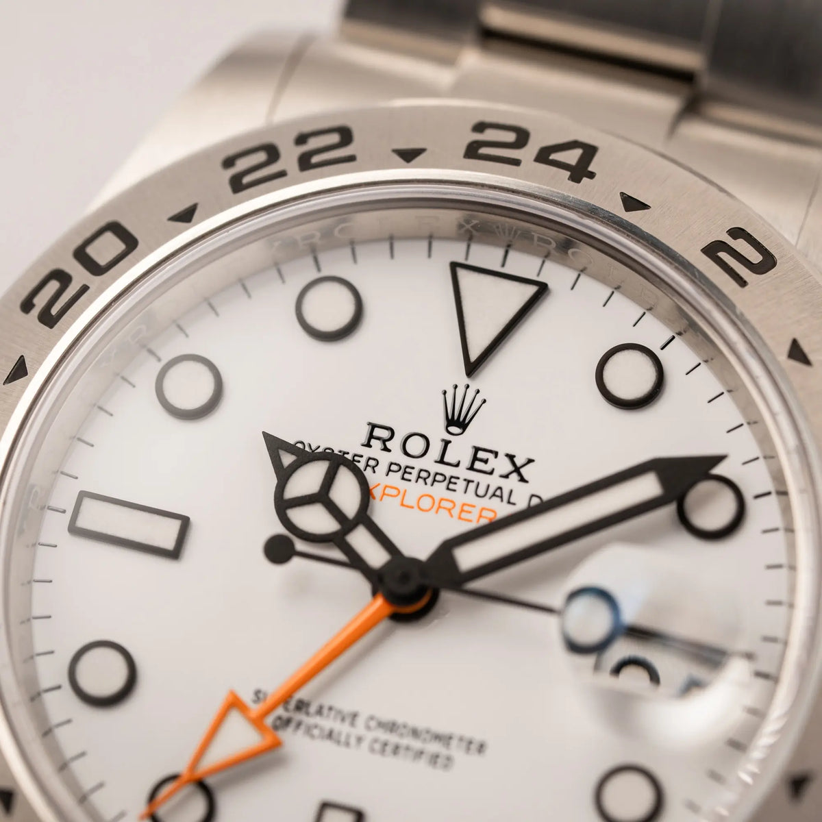 Detailaufnahme des Rolex-Schriftzugs bei 12 Uhr von der Rolex Explorer II der Referenz 226570 am Oyster-Stahlband mit dem weißen Polar-Zifferblatt und dem typischen orangen 24-Stunden-Zeiger