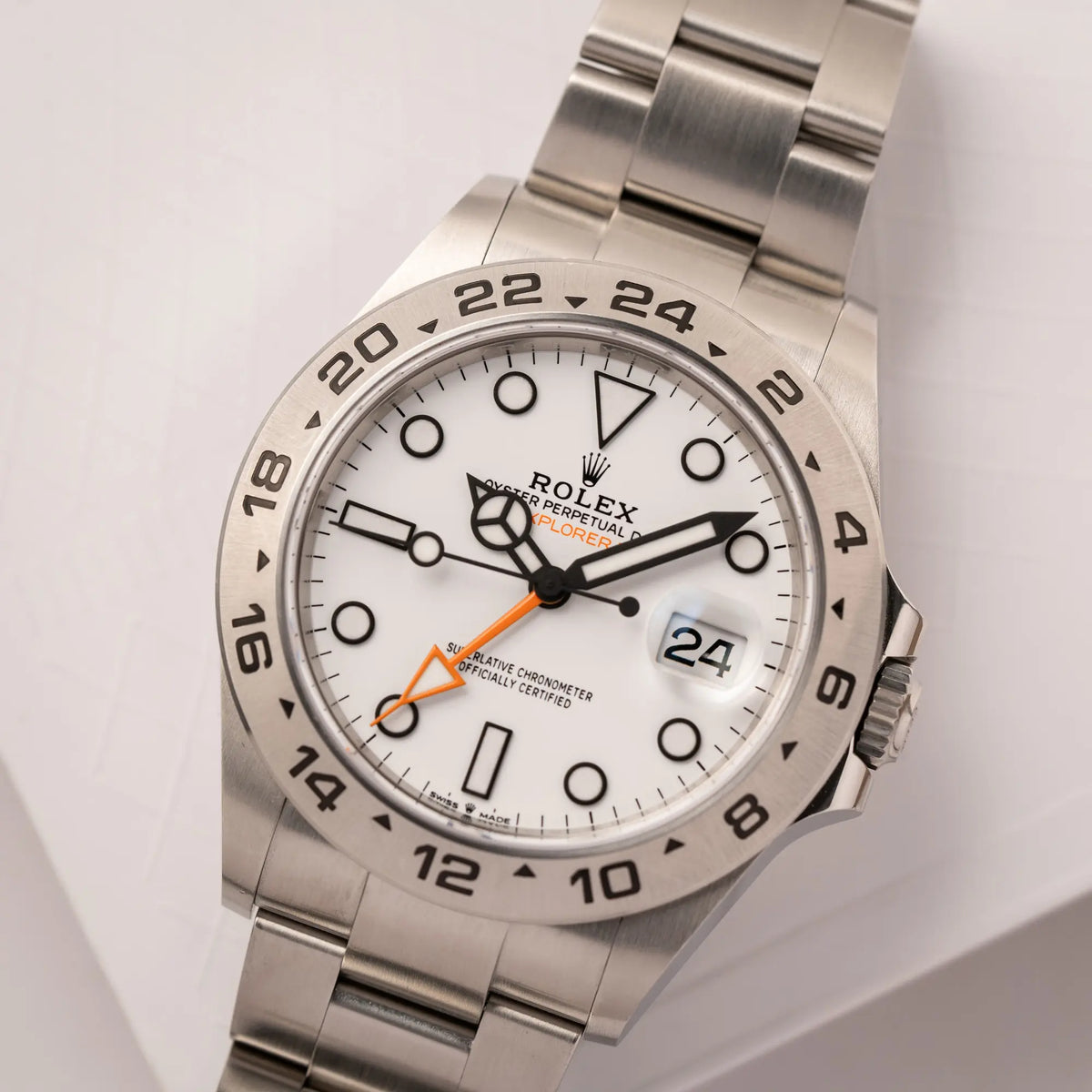 Nahe Produktfotografie der Rolex Explorer II der Referenz 226570 am Oyster-Stahlband mit dem weißen Polar-Zifferblatt und dem typischen orangen 24-Stunden-Zeiger