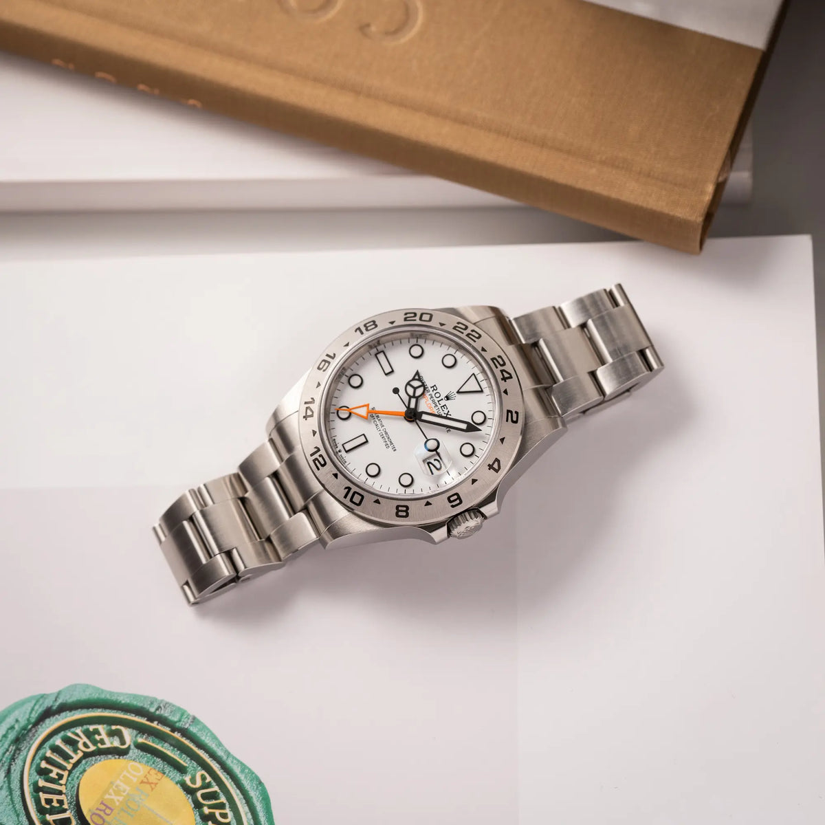 Produktfotografie der flach liegenden Rolex Explorer II der Referenz 226570 am Oyster-Stahlband mit dem weißen Polar-Zifferblatt und dem typischen orangen 24-Stunden-Zeiger