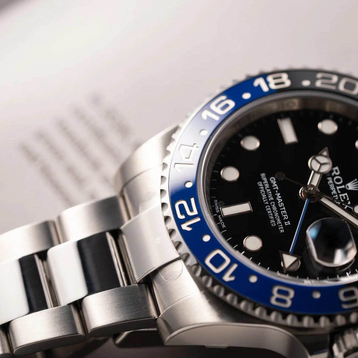 Detailaufnahme der Rolex GMT-Master II der Referenz 116710BLNR mit dem Nickname "Batman" mit der schwarz blauen Keramik-Lünette am Oyster-Stahlband im verklebten Neuzustand mit Fokus auf dem blauen Lünetten-Abschnitt