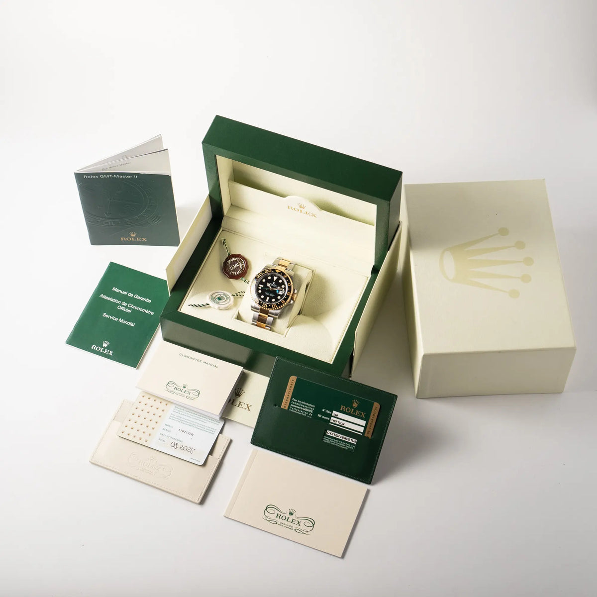 Lieferumfang zu der Rolex GMT-Master II der Referenz 116713LN in Stahl-Gold mit schwarzem Zifferblatt und dem grünen GMT-Zeige, bestehend aus Box mit Umkarton, originaler Garantiekarte, allen Booklets der Erstauslieferung, sowie von allen Booklets von einem offiziellen Rolex CPO Verkauf mit weißem Hangtag