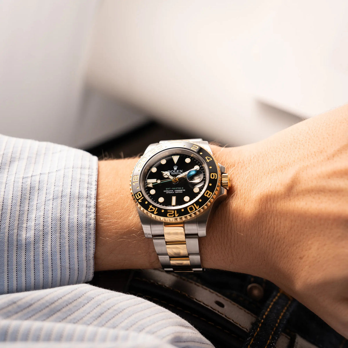 Mann trägt die Rolex GMT-Master II der Referenz 116713LN in Stahl-Gold mit schwarzem Zifferblatt und dem grünen GMT-Zeiger  an seinem Handgelenk