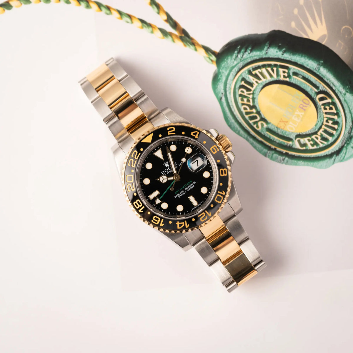 Rolex GMT-Master II der Referenz 116713LN in Stahl-Gold mit schwarzem Zifferblatt und dem grünen GMT-Zeiger  liegt flach auf einem Uhrenbuch
