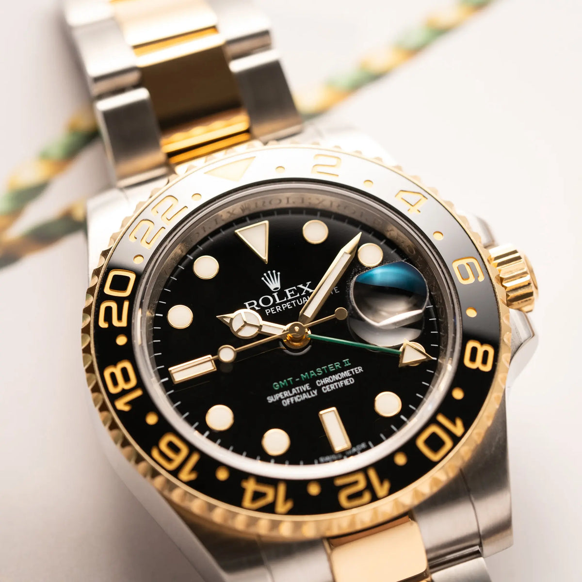 Detailaufnahme der Rolex GMT-Master II der Referenz 116713LN in Stahl-Gold mit schwarzem Zifferblatt und dem grünen GMT-Zeiger 