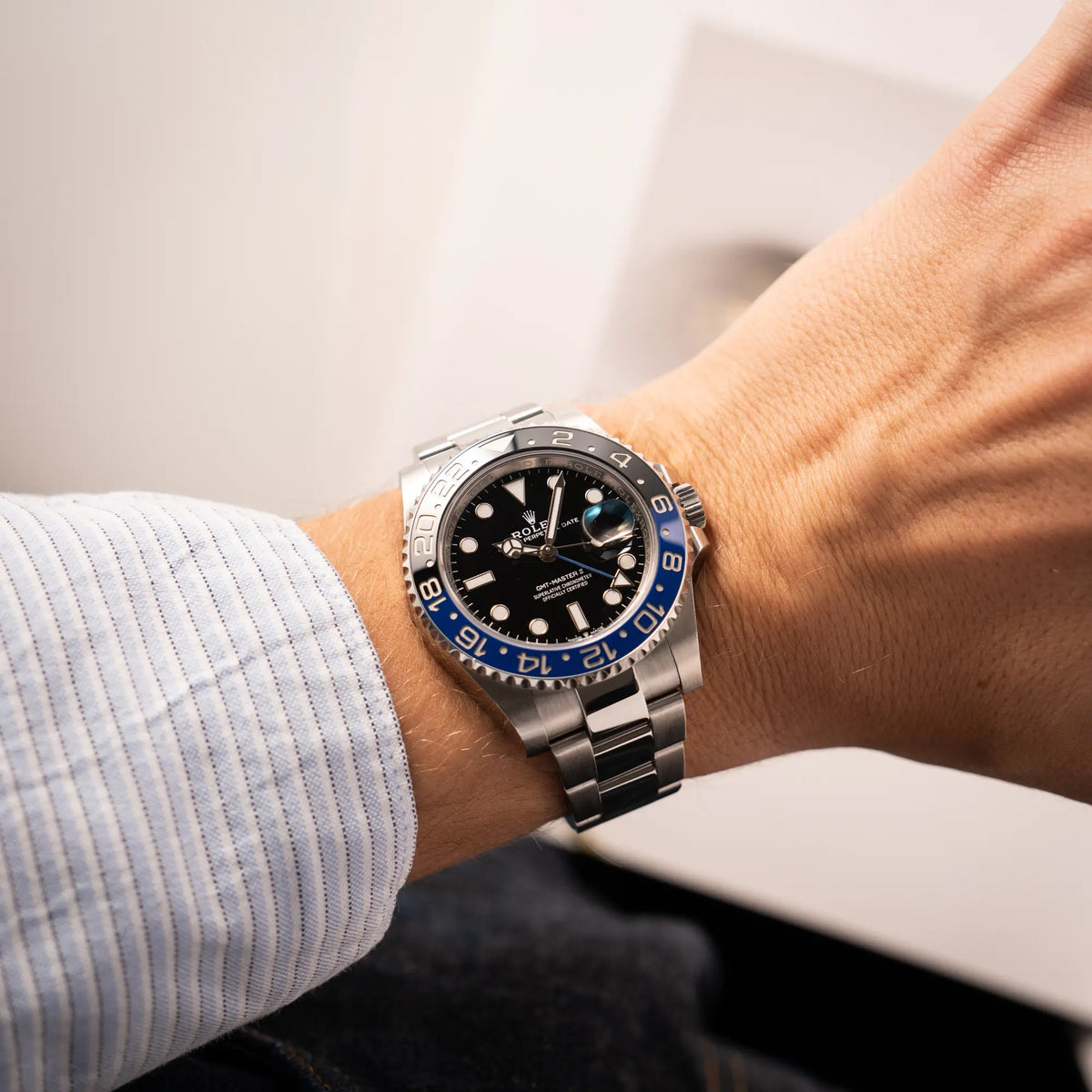 Mann trägt die Rolex GMT-Master II 126710BLNR mit dem Nickname Batman und der typischen Kombination aus blau-schwarzer Keramik-Lünette und schwarzem Zifferblatt an seinem Handgelenk