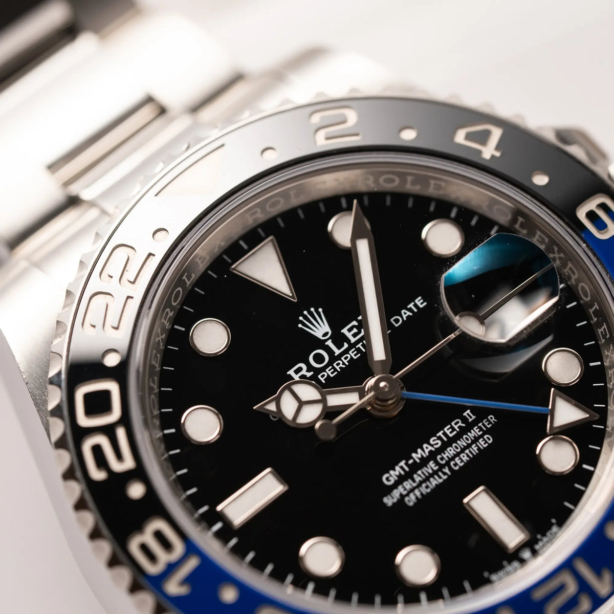 Nahaufnahme mit Fokus auf dem Zeigersatz von der Rolex GMT-Master II 126710BLNR mit dem Nickname Batman und der typischen Kombination aus blau-schwarzer Keramik-Lünette und schwarzem Zifferblatt