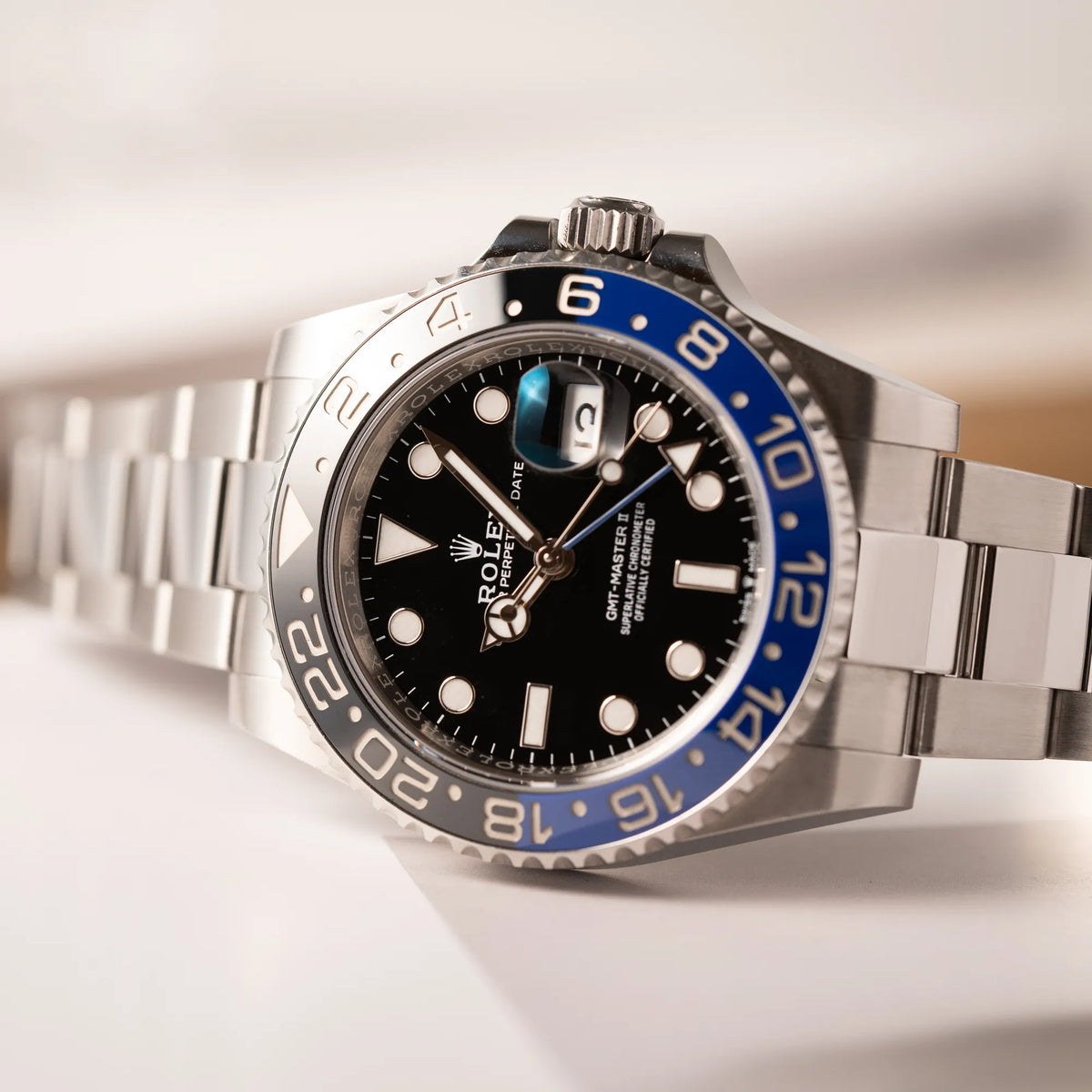 Detailaufnahme der seitlich auf dem Uhrengehäuse liegenden Rolex GMT-Master II 126710BLNR mit dem Nickname Batman und der typischen Kombination aus blau-schwarzer Keramik-Lünette und schwarzem Zifferblatt