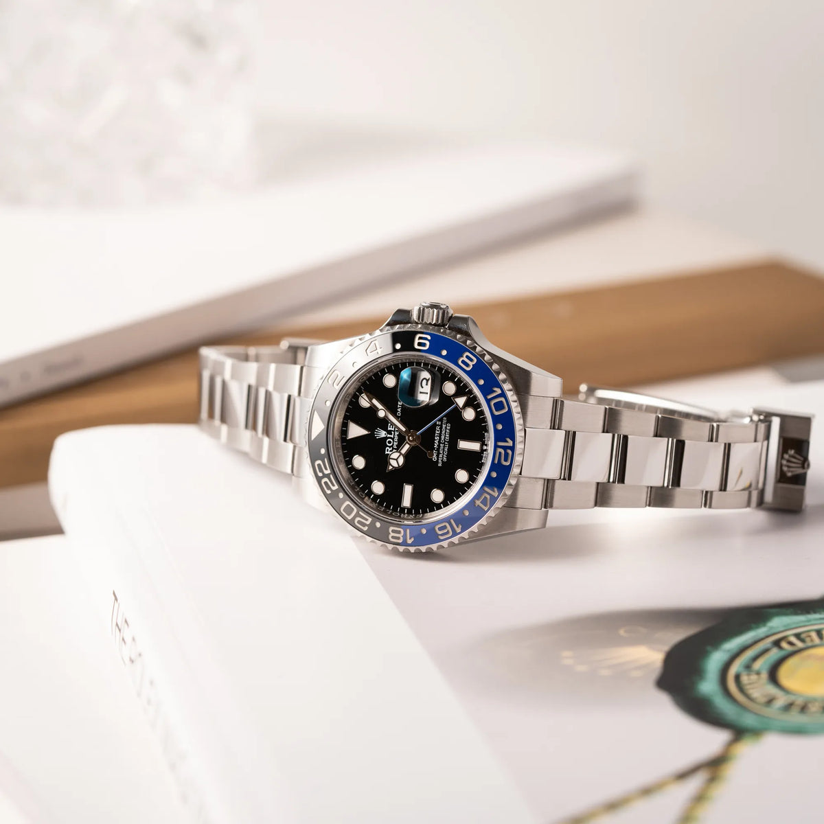 Produktfotografie der seitlich auf dem Gehäuse liegenden Rolex GMT-Master II 126710BLNR mit dem Nickname Batman und der typischen Kombination aus blau-schwarzer Keramik-Lünette und schwarzem Zifferblatt