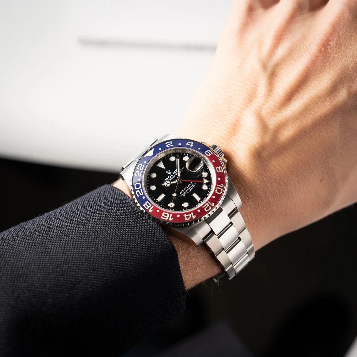 Mann präsentiert die Rolex GMT-Master II der Referenz 126710BLRO mit der blau-roten Pepsi-Lünette in Keramik am Oyster-Stahl-Armband im ungetragenen Zustand an seinem Handgelenk