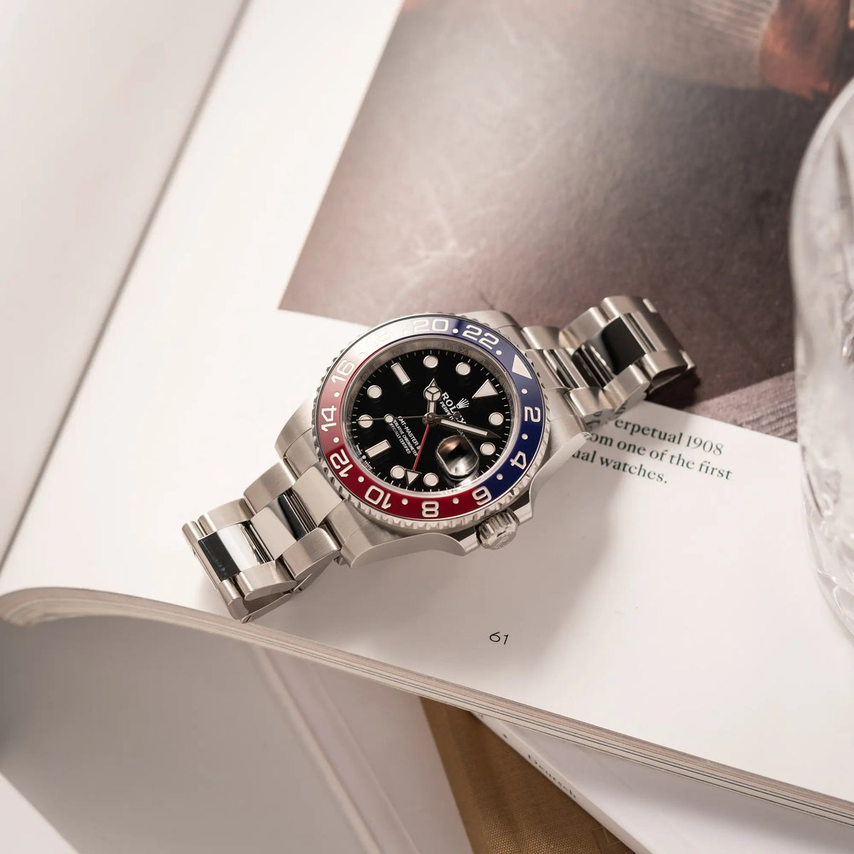 Rolex GMT-Master II der Referenz 126710BLRO mit der blau-roten Pepsi-Lünette in Keramik am Oyster-Stahl-Armband im ungetragenen Zustand liegt flach auf einem Uhrenbuch