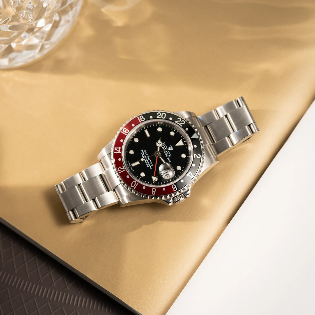 Produktfotografie der flach auf dem Band liegenden Rolex GMT-Master II 16710 mit der schwarz-roten "Coke" Aluminium-Lünetten-Einlage aus 2003 am Oyster Stahlband