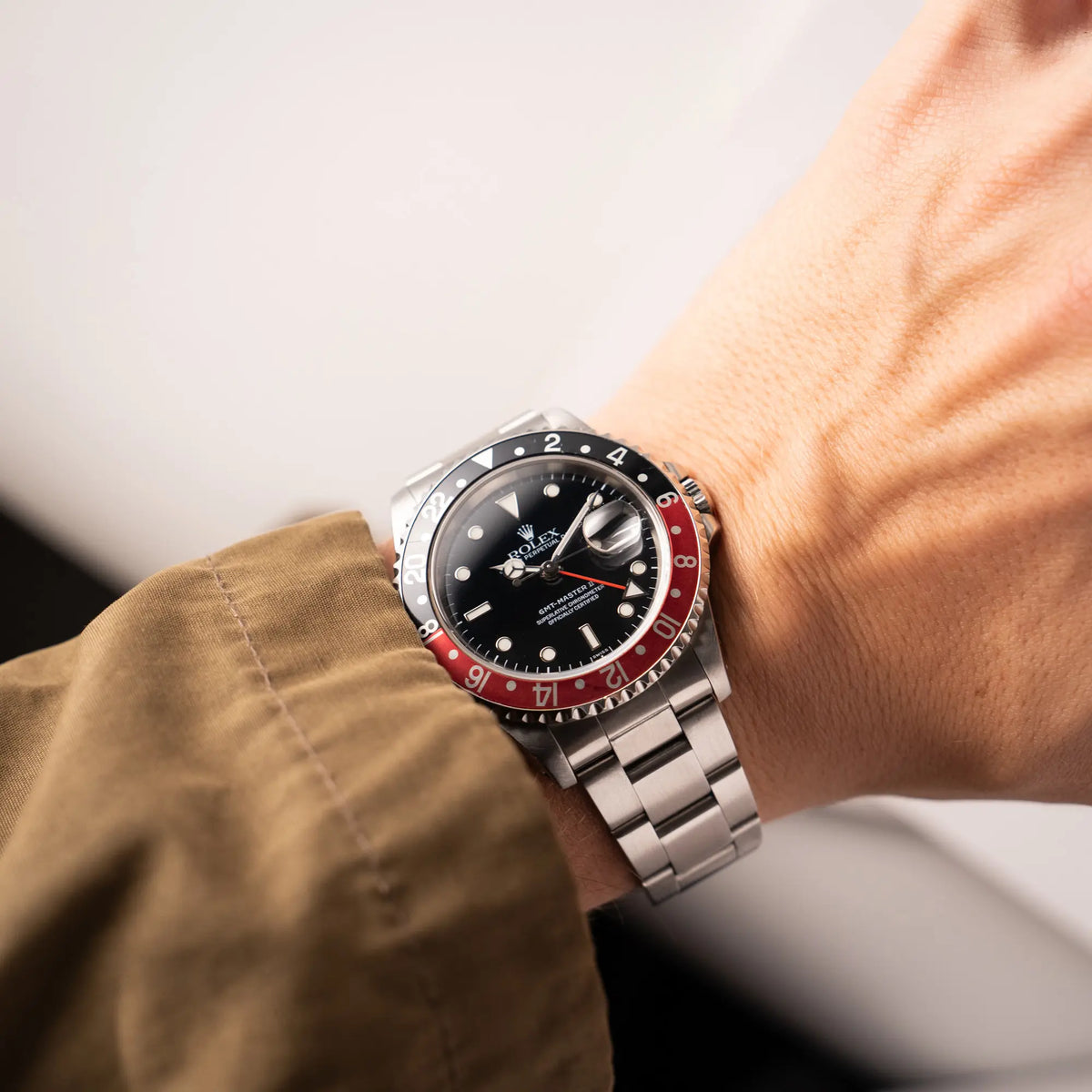 Mann präsentiert die Rolex GMT-Master II der Referenz 16710  2000 mit  schwarz-roter Coke-Lünette und dem für das Jahr 2000 typische "Swiss Only" - Zifferblatt an seinem Handgelenk