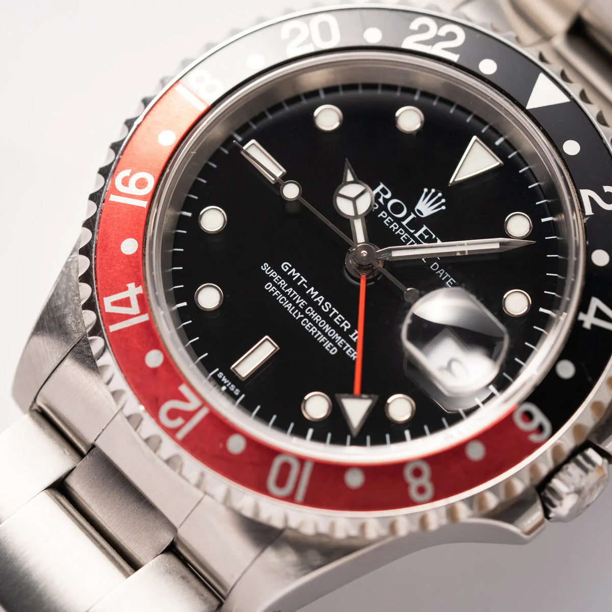 Nahaufnahme der Rolex GMT-Master II der Referenz 16710  2000 mit  schwarz-roter Coke-Lünette und dem für das Jahr 2000 typische "Swiss Only" - Zifferblatt