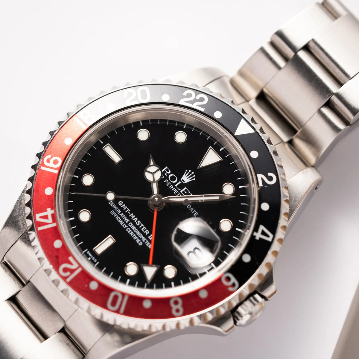 Detailaufnahme der Rolex GMT-Master II der Referenz 16710  2000 mit  schwarz-roter Coke-Lünette und dem für das Jahr 2000 typische "Swiss Only" - Zifferblatt